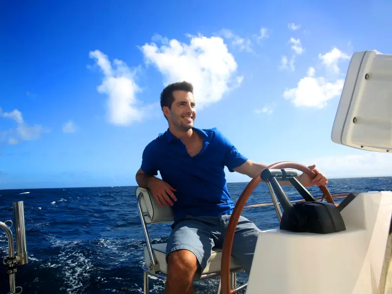 Kapitän am Steuer einer Luxusyacht mit Blick auf die Alpen