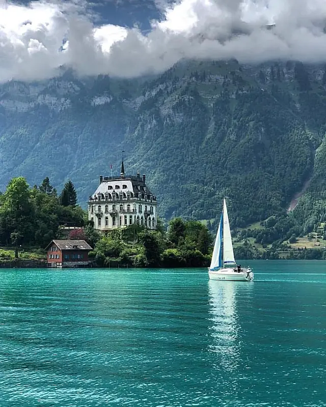 Yacht auf ruhigem Wasser mit Blick auf die Alpen