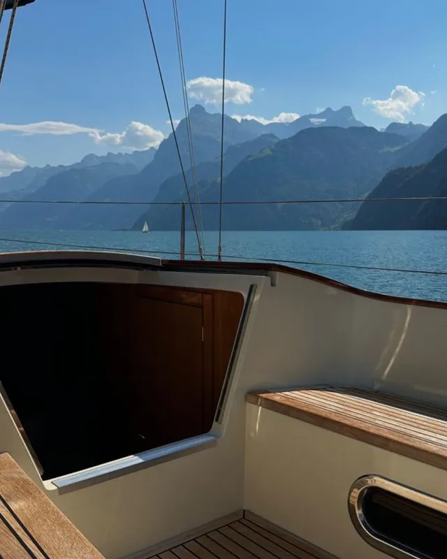 Yacht auf ruhigem Wasser mit Blick auf die Alpen